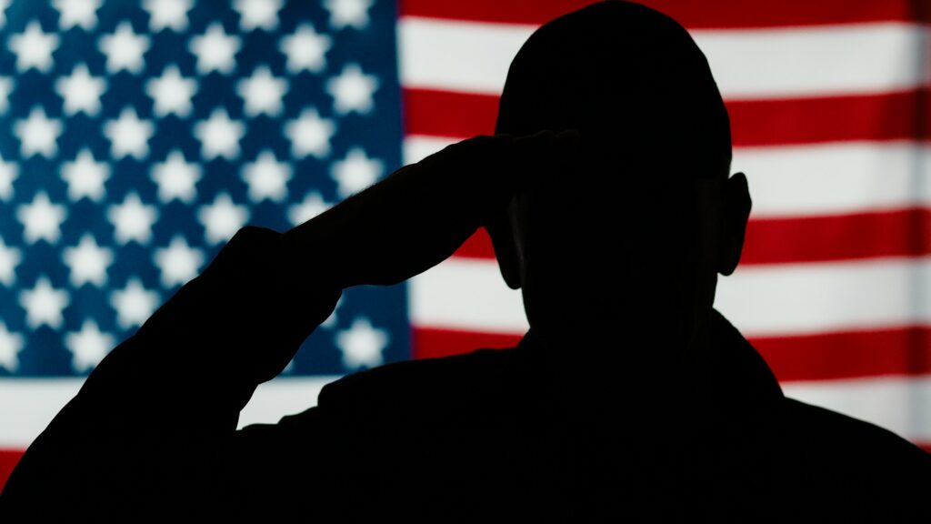 American military veteran stands at attention with military flag salute.